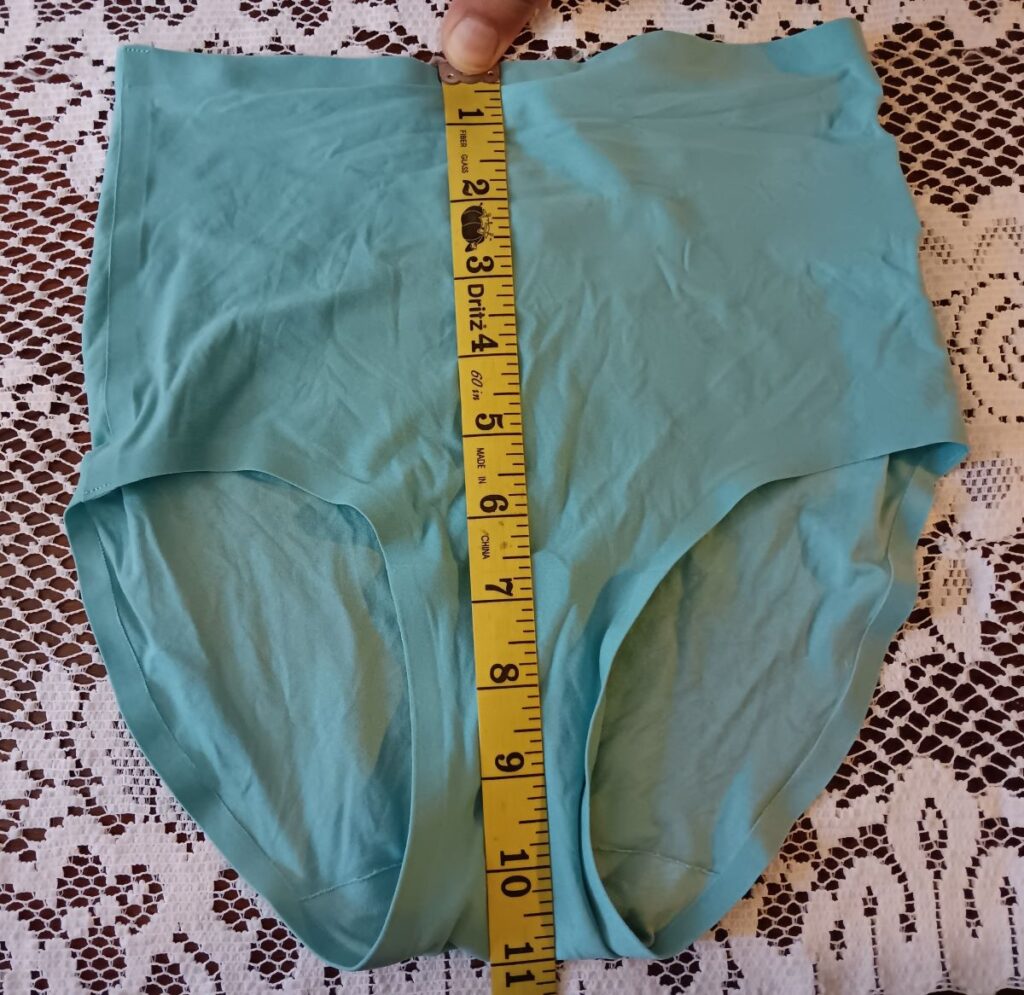 Front image of the high waist brief laying flat with a measuring tape for rise.