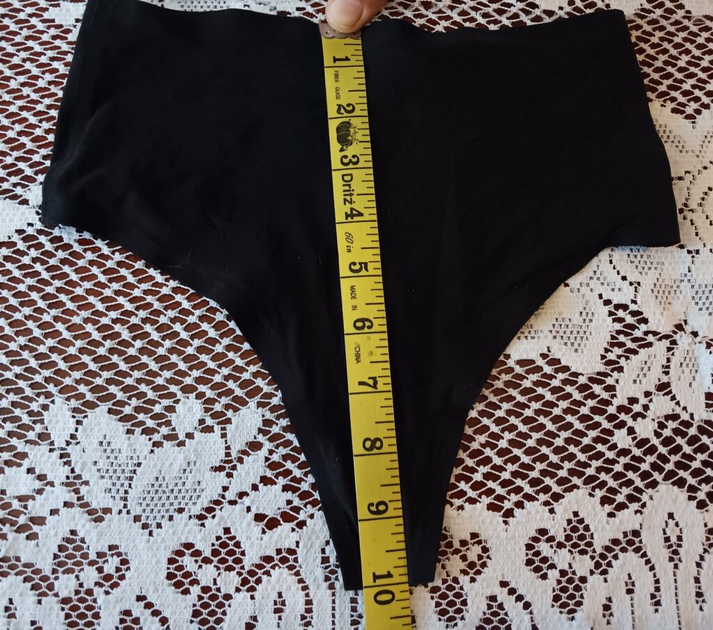 Front of the retro thong laying flat with a measuring tape for rise